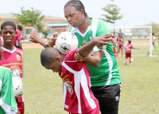 Kanu Nwankwo – helping a child with ball balancing at Greensprings Kanu Football Camp