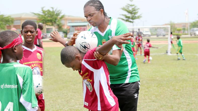 Kanu Nwankwo – helping a child with ball balancing at Greensprings Kanu Football Camp